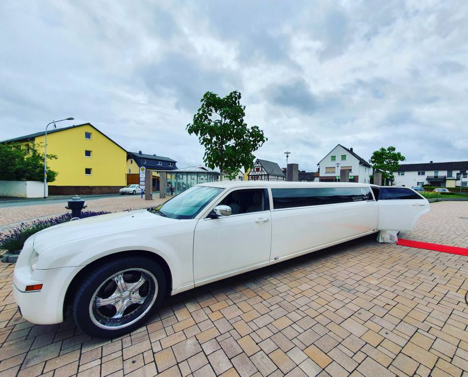 Weiße Chrysler 300c Stretchlimousine mit rotem Teppich bei einer Hochzeit